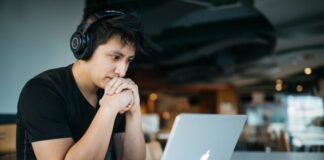 Mistakes You Should Avoid While Online Betting man wearing headphones while sitting on chair in front of MacBook