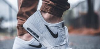 Essential Footwear for Modern Living person wearing white Nike running shoes standing on black concrete path