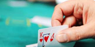 When to Hit in Blackjack: Understanding the Basics of Casino Strategy in 2023 A man at a blackjack table with a focused expression, holding cards showing an ace and a king.