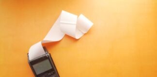 Tips for Catching Up Past Due Bills a cell phone sitting on top of a table next to a roll of paper