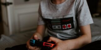 5 Ways to Earn Money Through Video Games kid sitting on gray bed while playing