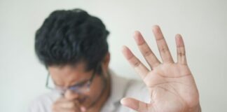 Coughing With No Explanation? This Could Be the Root Cause a man holding his hand up in front of his face