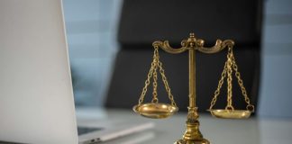 When Is It the Right Move to Take a Plea Bargain? Golden justice scales on a desk beside a laptop, symbolizing law and balance.