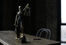 3 Ways a Criminal Law Attorney Can Help If You Find Yourself in Trouble Lady Justice figurine on wooden table in dimly lit room symbolizes law and fairness.