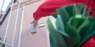 Home Security Tips to Help Protect Your Physical and Digital Lives—What Actually Works? Close-up of a person using a security keypad on a gate, highlighting home access control.