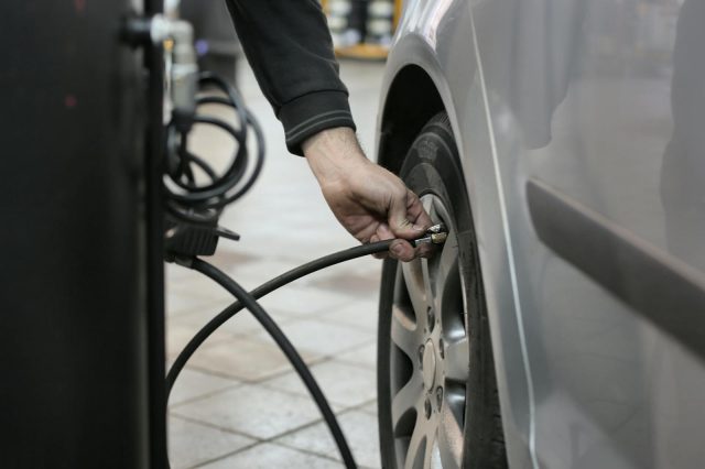 Photo by Andrea Piacquadio Mechanic inflating a car tire inside an auto repair shop, ensuring optimal tire pressure.