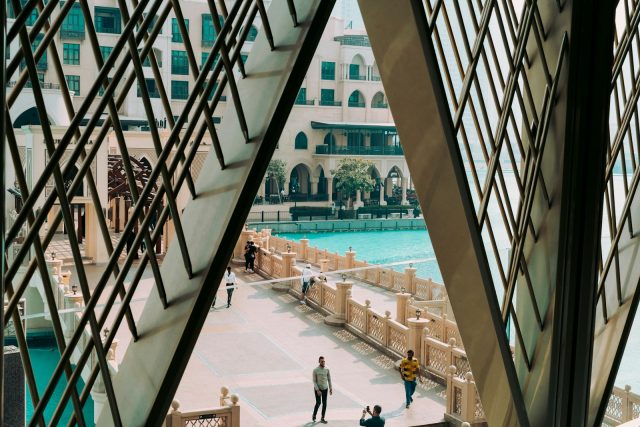 people walking on bridge beside pool in front of building
