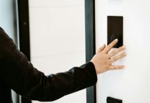 How Smart Door Locks Support a Contactless Lifestyle a person is pressing a button on a white wall
