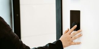 How Smart Door Locks Support a Contactless Lifestyle a person is pressing a button on a white wall